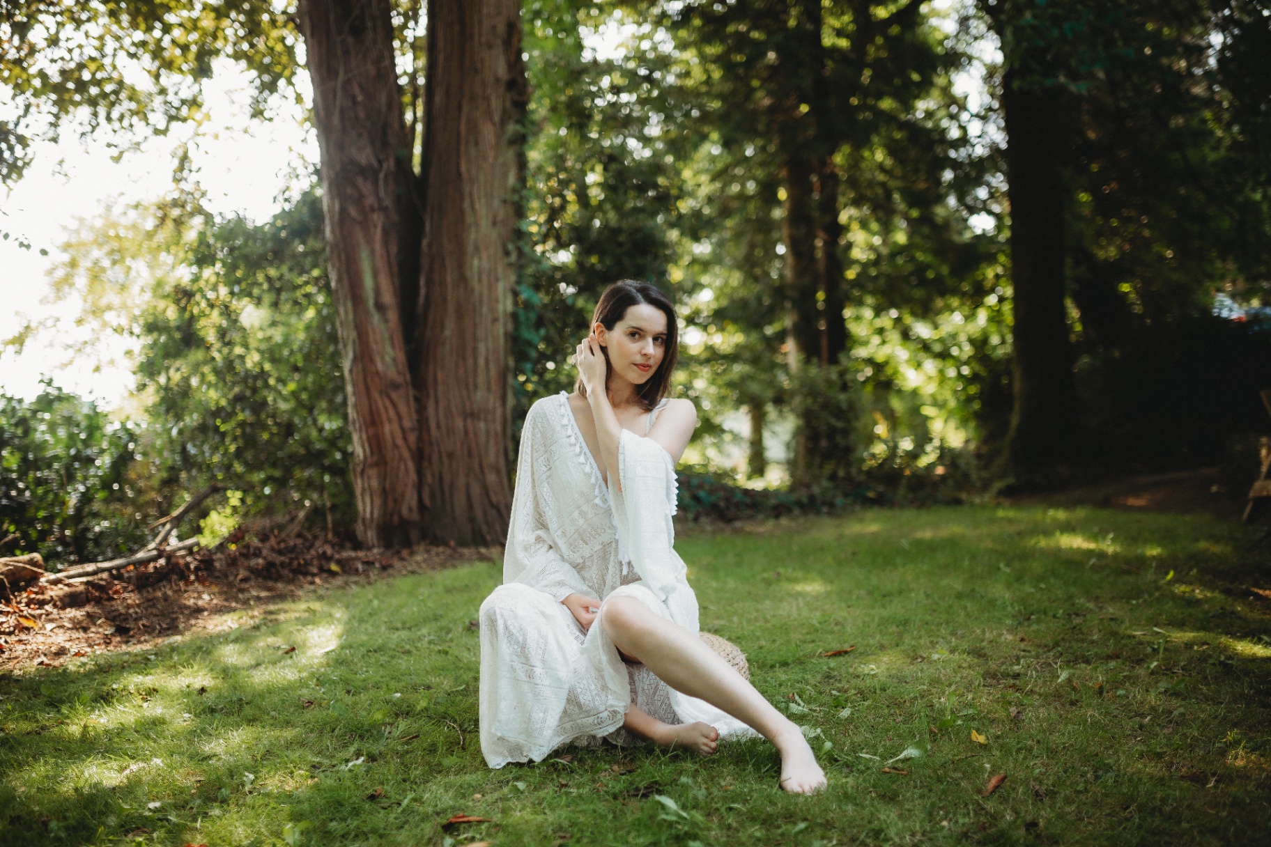 Rachel sitting on grass in a sunlit woodland